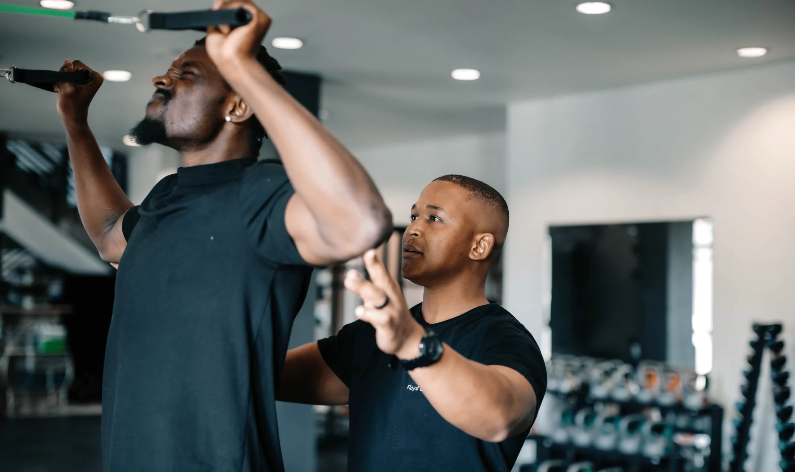 Who We Are 12 Sports physiotherapist assisting athlete with resistance band upper body stretch