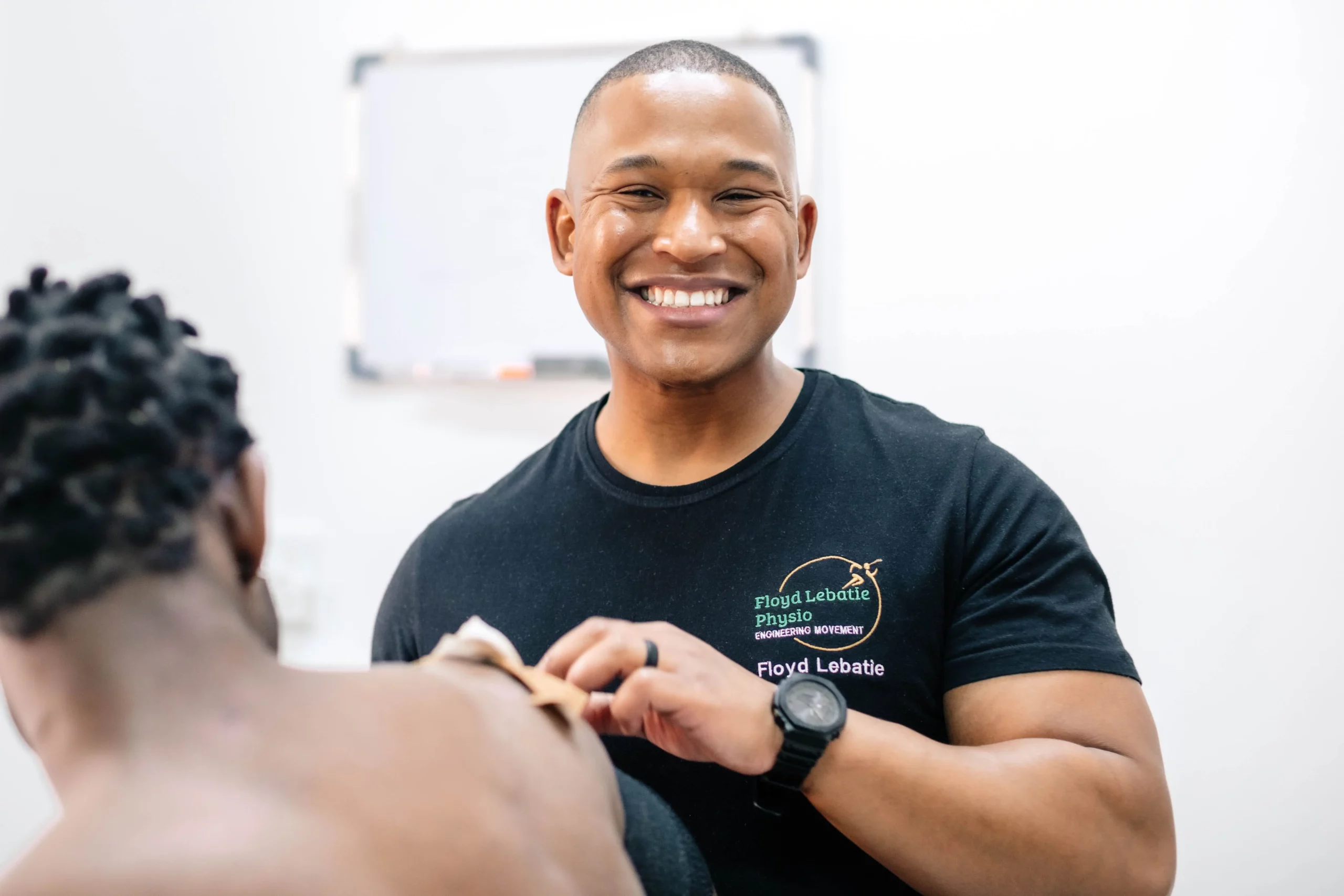 Closeup of Floyd Lebatie physiotherapist treating patient's right shoulder